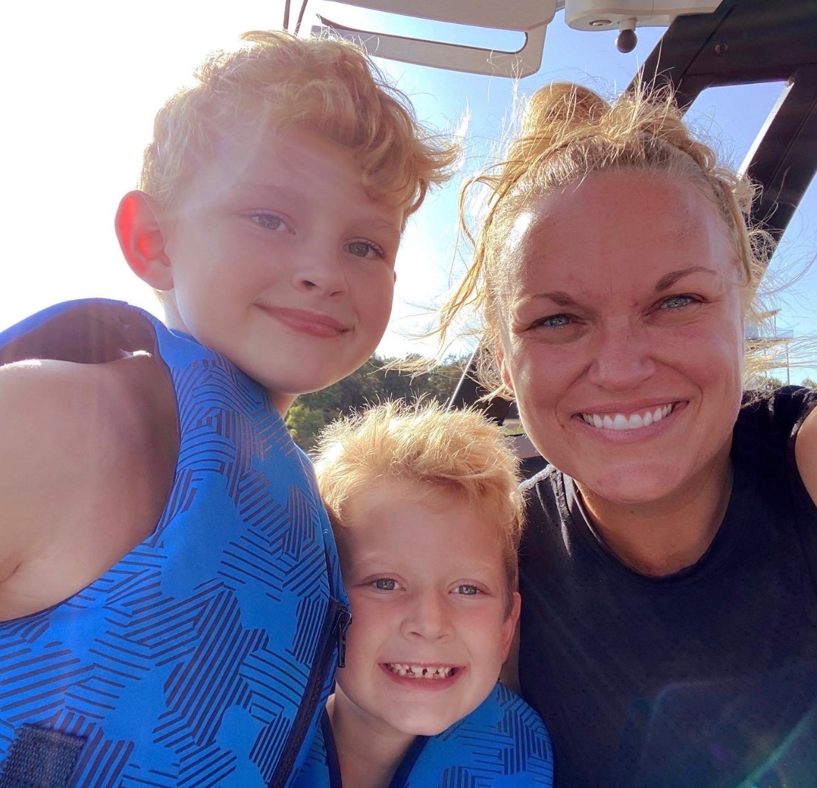 Amber with her two sons, all smiling in life jackets on a boat