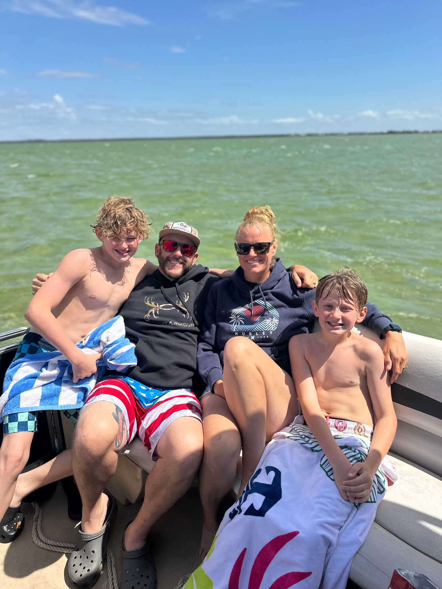 Amber with her husband and two sons sitting together on a boat on the water