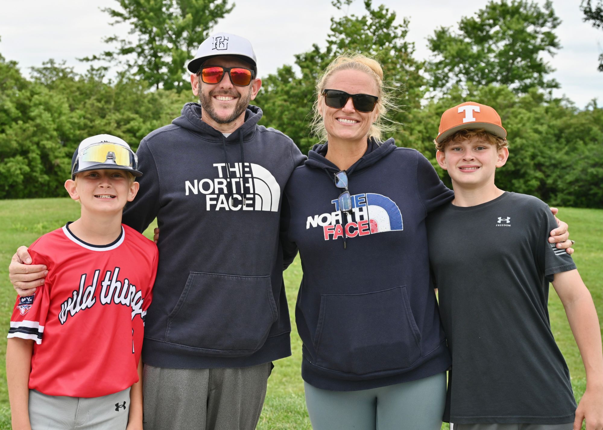 Amber with her husband and two sons, arm in arm on a green field